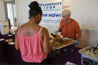 A woman is served a meal by another at a community event